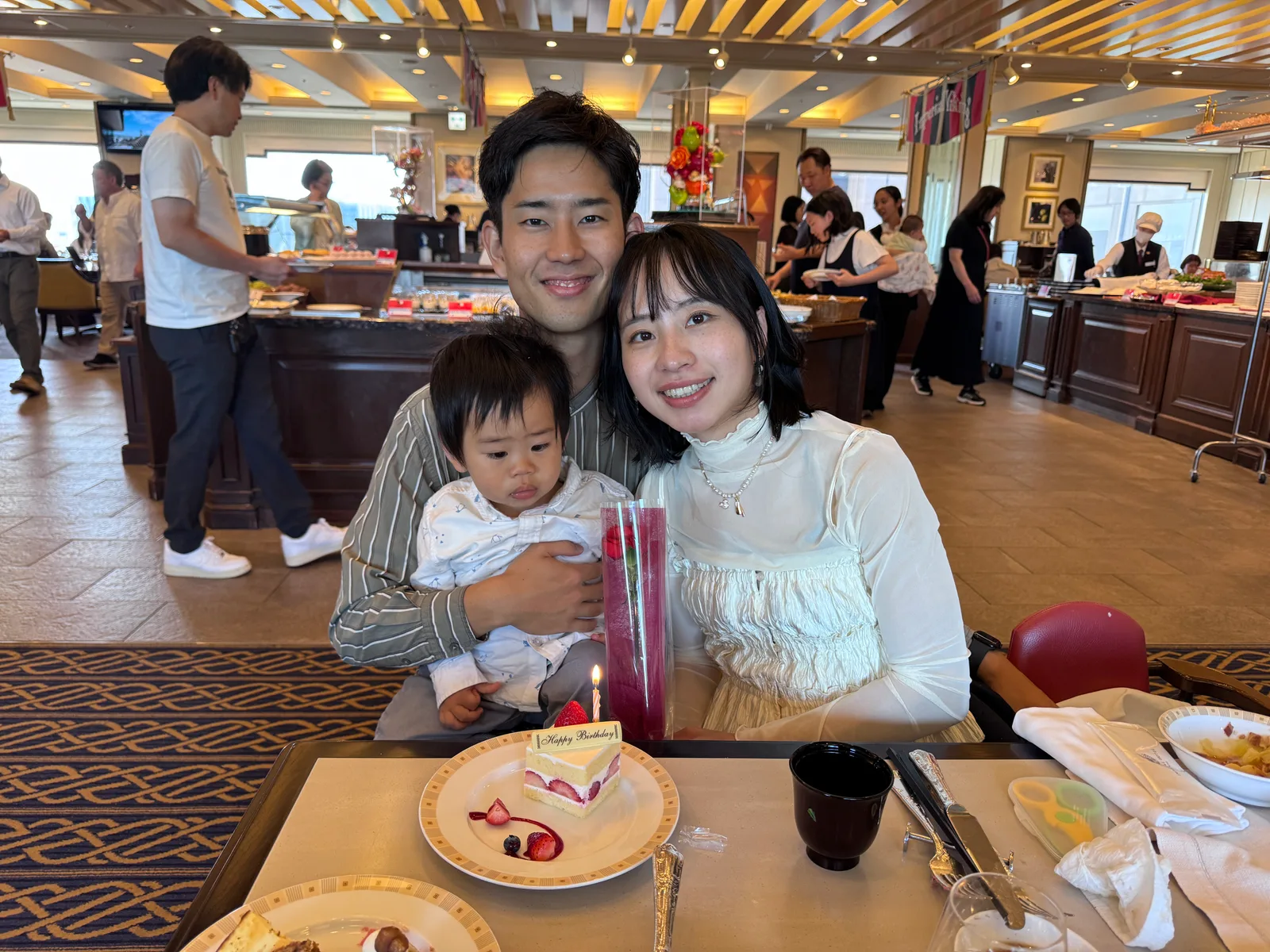 在帝國飯店自助餐廳圍著生日蛋糕的一家人