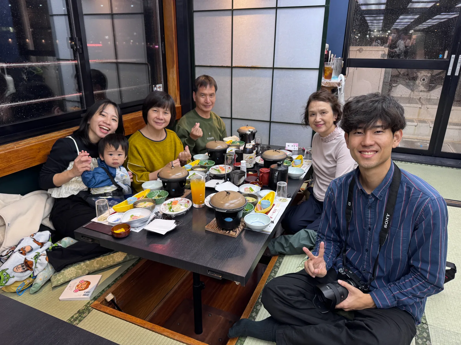 在下嵌式暖桌和室圍著會席料理的三代同堂家庭