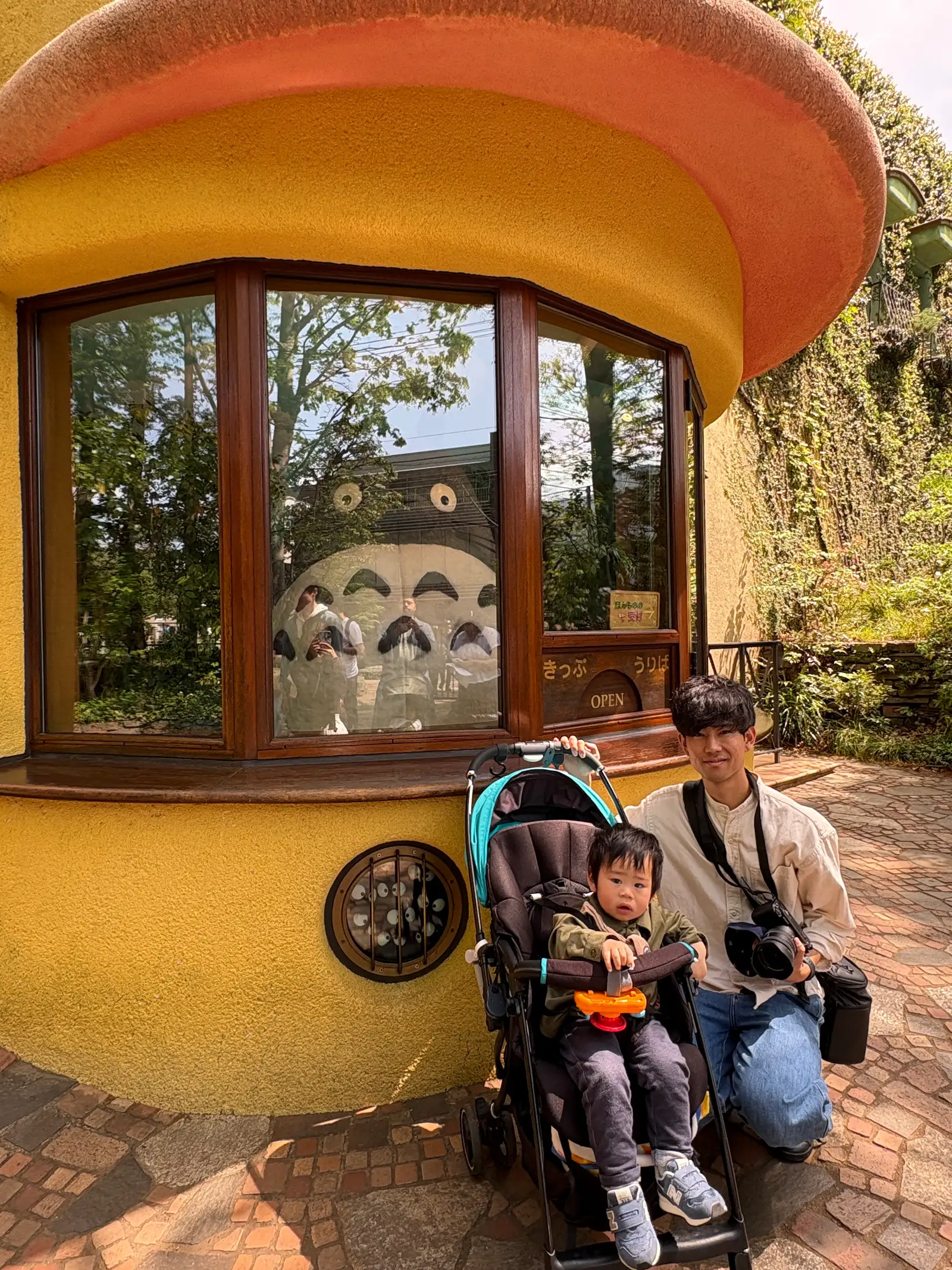 ジブリ美術館の入口。トトロが受付にいる「きっぷうりば」の窓と、ベビーカーの子供と父親