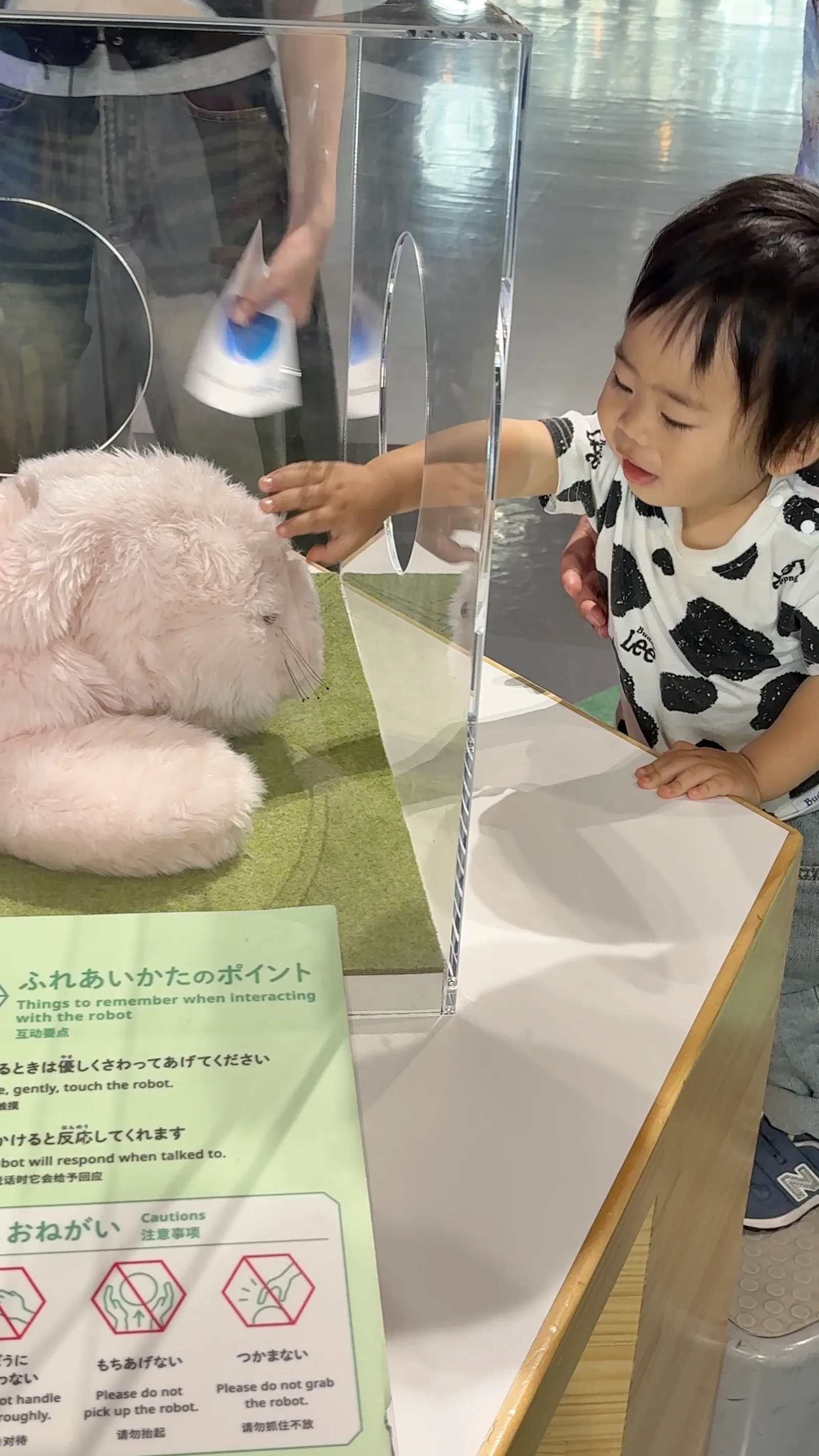 孩子在日本科學未來館輕輕觸摸療癒機器人「Paro」